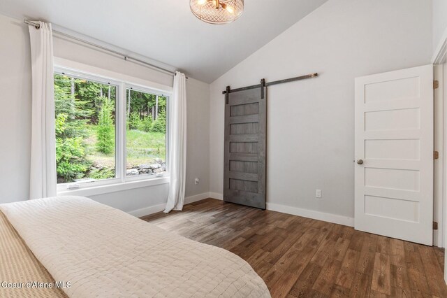 130 Cedar Shls, Sagle, ID 83860 - bedroom featuring lofted ceiling, a barn door, wood finished floors, and baseboards