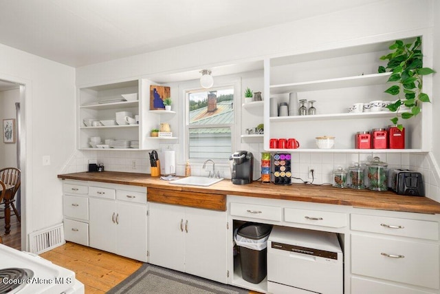 kitchen featuring a sink, wood counters, and open shelves