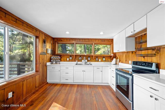 24010 N Bridge Lake Rd, Rathdrum, ID 83858 - kitchen with stainless steel range with electric cooktop, a sink, hardwood / wood-style flooring, wood walls, and light countertops