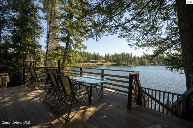 24010 N Bridge Lake Rd, Rathdrum, ID 83858 - deck with outdoor dining area, a water view, and a wooded view
