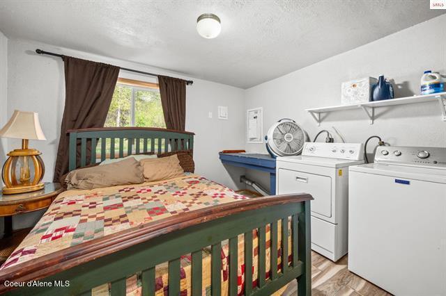 24010 N Bridge Lake Rd, Rathdrum, ID 83858 - bedroom with light wood-style floors, washer and clothes dryer, and a textured ceiling