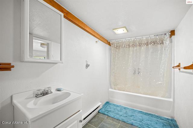24010 N Bridge Lake Rd, Rathdrum, ID 83858 - bathroom with a baseboard heating unit, shower / bath combination with curtain, and vanity