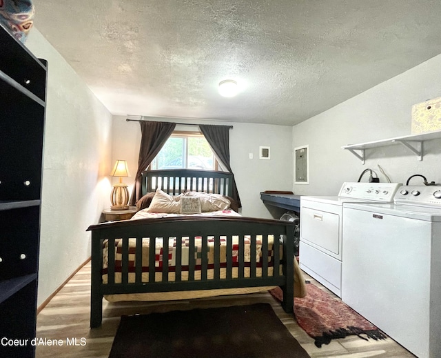 24010 N Bridge Lake Rd, Rathdrum, ID 83858 - bedroom featuring separate washer and dryer, light wood-type flooring, a textured ceiling, and electric panel
