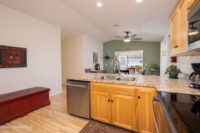 kitchen featuring appliances with stainless steel finishes, a sink, a peninsula, light wood-style floors, and a ceiling fan