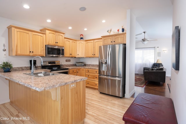 kitchen with stainless steel appliances, a sink, light brown cabinetry, a peninsula, and light countertops