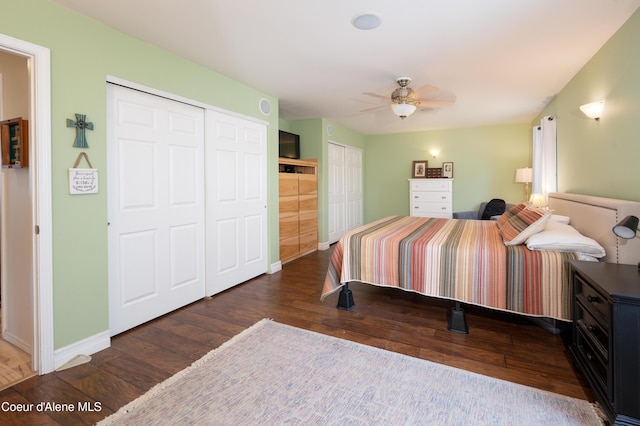 bedroom featuring hardwood / wood-style flooring, multiple closets, baseboards, and ceiling fan