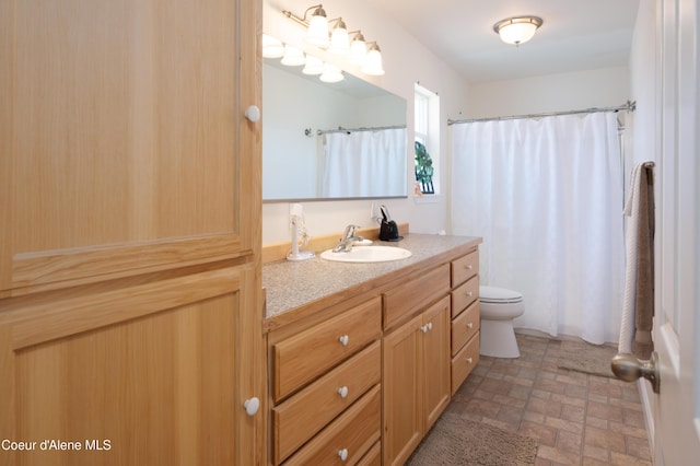 full bath featuring toilet, vanity, brick patterned floors, and curtained shower