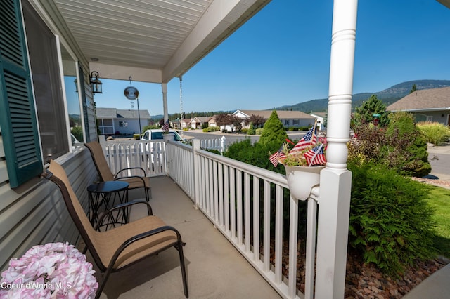 balcony featuring covered porch, a mountain view, and a residential view