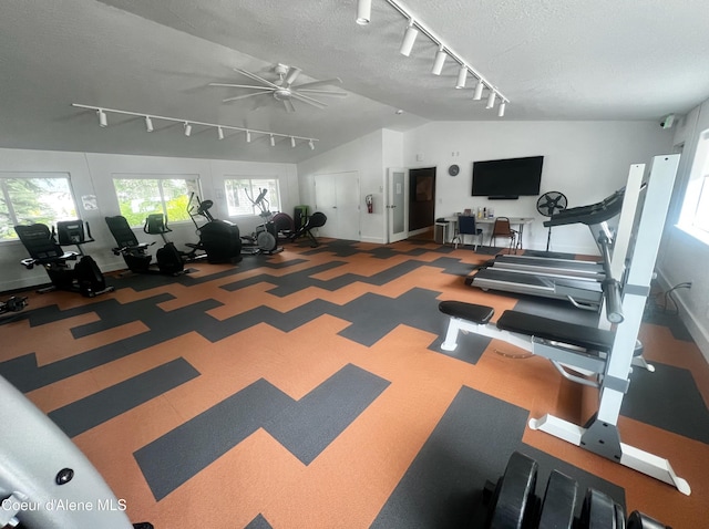 workout area with rail lighting, ceiling fan, a textured ceiling, vaulted ceiling, and baseboards