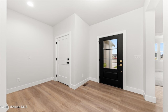 foyer entrance with light wood finished floors, baseboards, and healthy amount of natural light