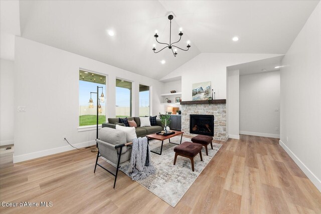 living room featuring light wood-style flooring, a stone fireplace, baseboards, a chandelier, and high vaulted ceiling