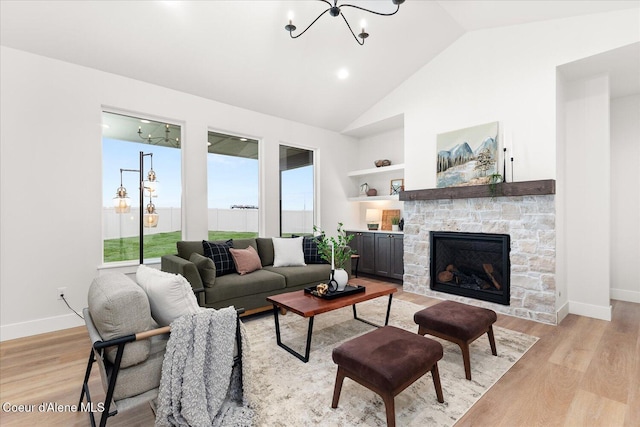 living area with a chandelier, plenty of natural light, lofted ceiling, light wood-type flooring, and a stone fireplace