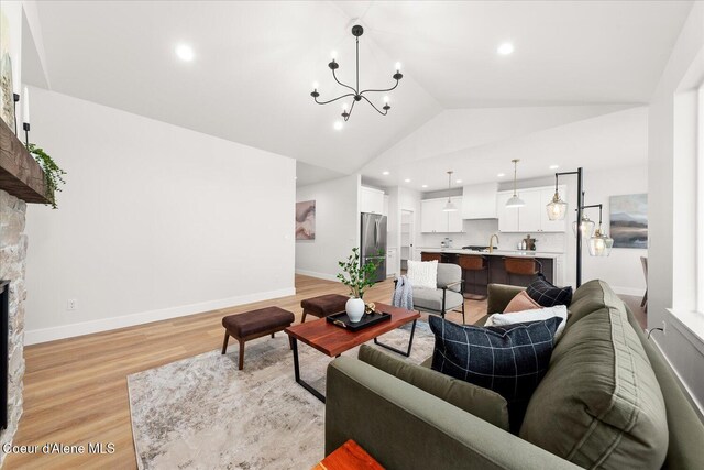 living area with a chandelier, lofted ceiling, recessed lighting, light wood finished floors, and a fireplace