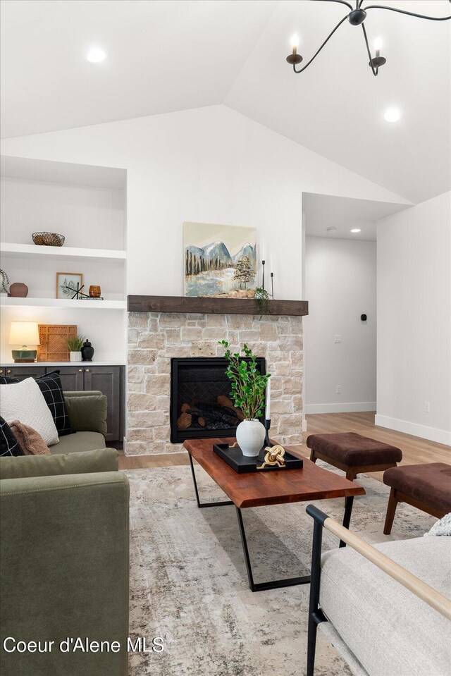 living room featuring lofted ceiling, a stone fireplace, wood finished floors, recessed lighting, and baseboards