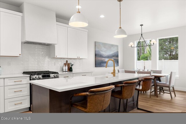 kitchen with a sink, light countertops, light wood-type flooring, white cabinets, and recessed lighting
