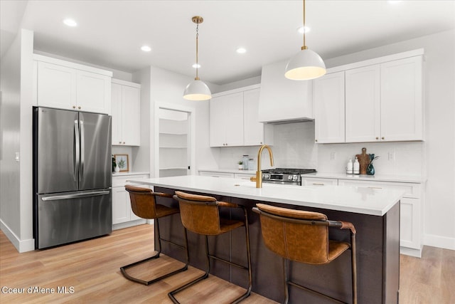 kitchen with freestanding refrigerator, light wood-type flooring, light countertops, white cabinets, and recessed lighting