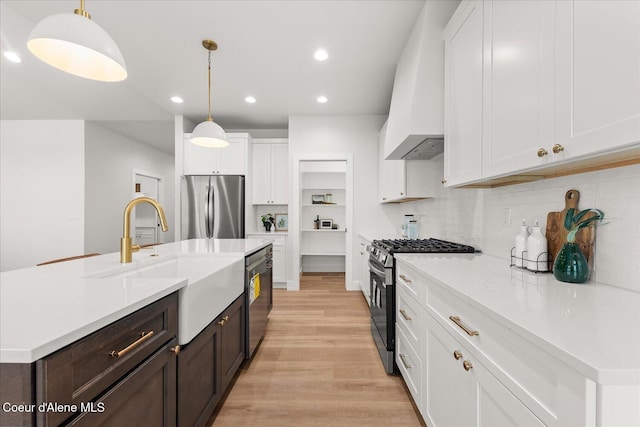 kitchen with appliances with stainless steel finishes, a sink, white cabinetry, recessed lighting, and light countertops