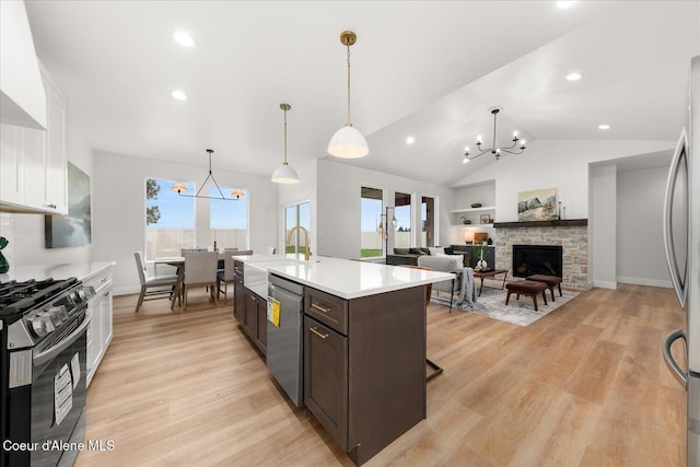 kitchen with appliances with stainless steel finishes, a sink, a chandelier, light countertops, and light wood finished floors