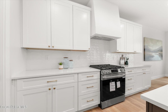 kitchen featuring stainless steel range with gas stovetop, premium range hood, light wood-style flooring, and light countertops