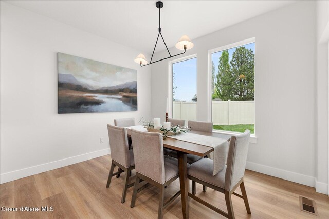 dining space featuring light wood-type flooring, baseboards, and a chandelier