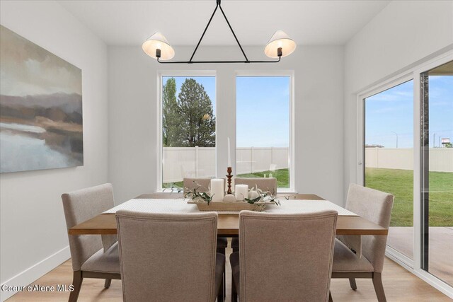 dining space with light wood-type flooring, a chandelier, and plenty of natural light