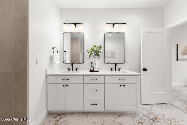 bathroom featuring marble finish floors, baseboards, and double vanity