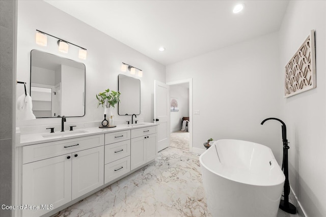 bathroom with marble tiled flooring, double vanity, a freestanding tub, baseboards, and recessed lighting