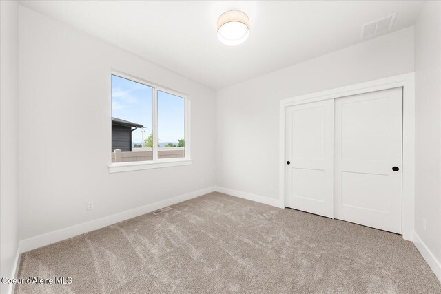 unfurnished bedroom with carpet floors, baseboards, and a closet