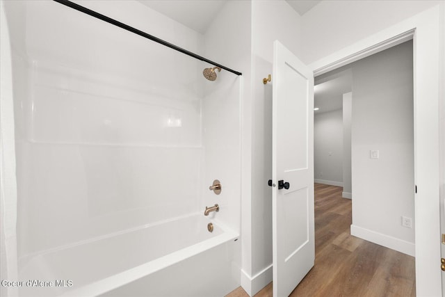 bathroom featuring baseboards, wood finished floors, and  shower combination