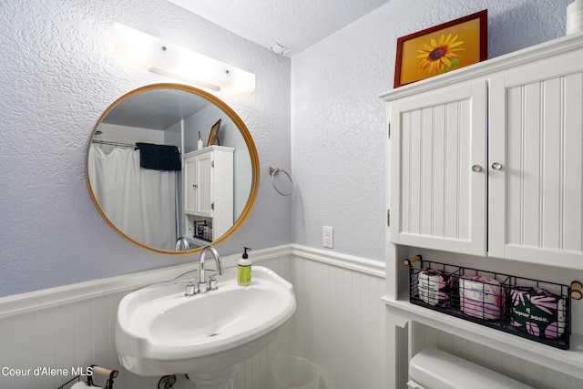 610 W Emma Ave, Coeur Dalene, ID 83814 - bathroom with wainscoting, a sink, a textured wall, a textured ceiling, and a shower with shower curtain