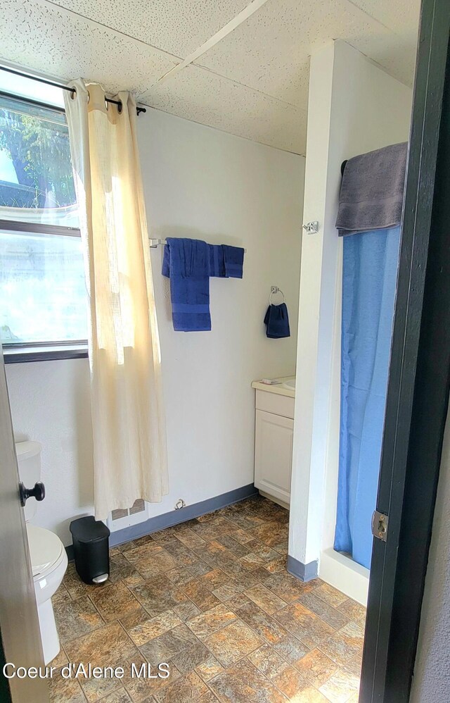 610 W Emma Ave, Coeur Dalene, ID 83814 - bathroom featuring toilet, a shower with shower curtain, stone finish flooring, and baseboards