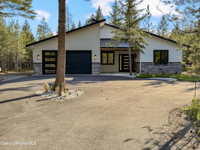 624 Satchel Dr, Spirit Lake, ID 83869 - view of front facade with stone siding, asphalt driveway, a garage, and a standing seam roof