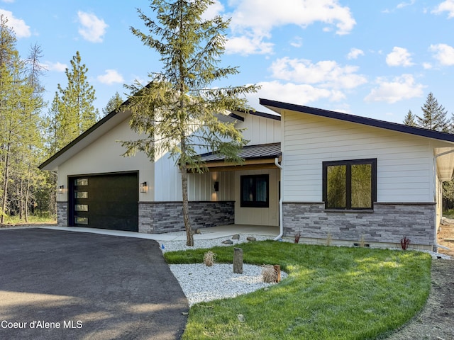 624 Satchel Dr, Spirit Lake, ID 83869 - view of front of home with stone siding, driveway, an attached garage, a standing seam roof, and a front yard