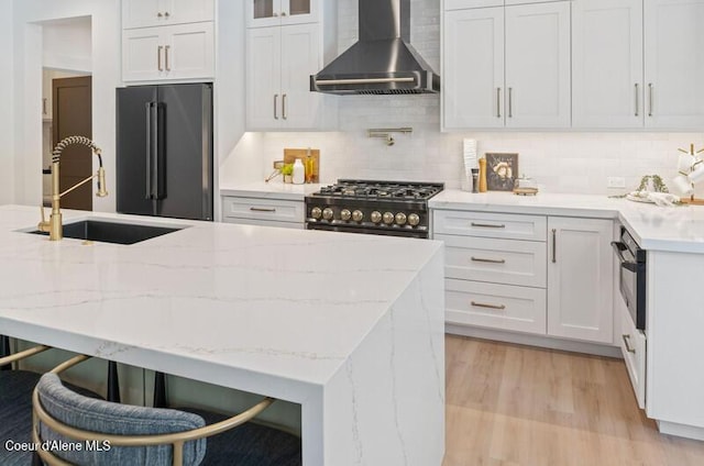 624 Satchel Dr, Spirit Lake, ID 83869 - kitchen featuring wall chimney range hood, high end fridge, a sink, gas range oven, and light wood-type flooring