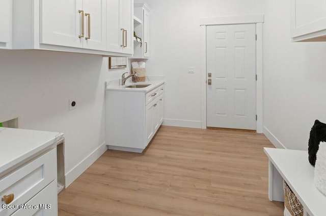 624 Satchel Dr, Spirit Lake, ID 83869 - washroom featuring cabinet space, baseboards, and light wood-style flooring