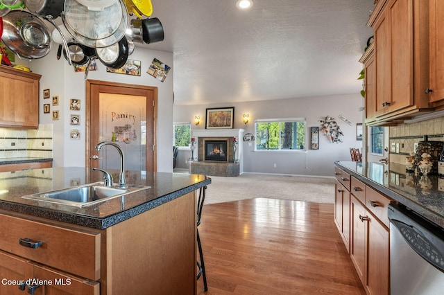 9798 N Willowherb Ct, Hauser, ID 83854 - kitchen with dishwasher, a sink, dark countertops, a glass covered fireplace, and open floor plan