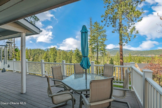 9798 N Willowherb Ct, Hauser, ID 83854 - wooden terrace featuring a mountain view, outdoor dining area, and a wooded view