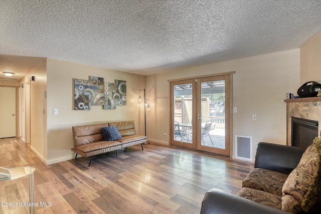 4413 W Pleasant Ln, Post Falls, ID 83854 - living area featuring a textured ceiling, light wood finished floors, french doors, a premium fireplace, and baseboards