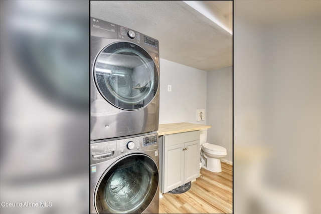 4413 W Pleasant Ln, Post Falls, ID 83854 - laundry area with stacked washer and clothes dryer, light wood-style floors, and a textured ceiling