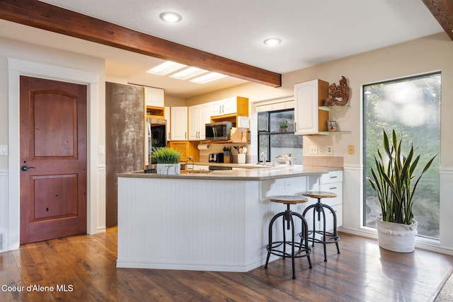 11624 N W Newman Lake Dr, Newman Lake, WA 99025 - kitchen featuring stainless steel microwave, beamed ceiling, dark wood-type flooring, a peninsula, and a kitchen bar