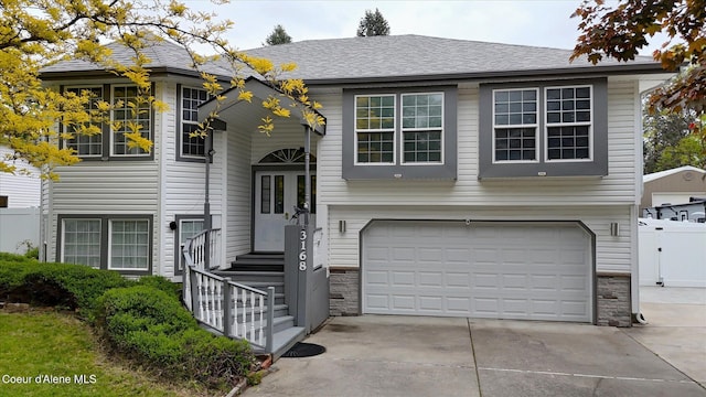 3168 N 9th St, Coeur Dalene, ID 83815 - raised ranch with an attached garage, stone siding, and driveway