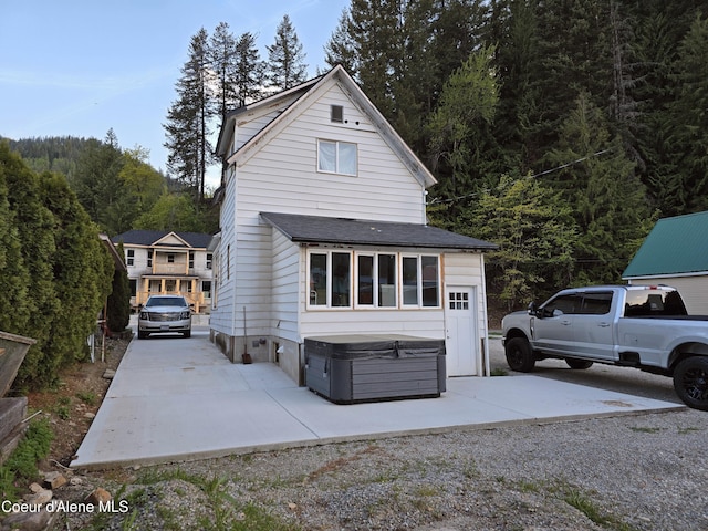 117 River St, Wallace, ID 83873 - view of front of home featuring a hot tub, driveway, and a forest view