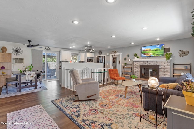 living room with ceiling fan, recessed lighting, wood finished floors, a fireplace, and an AC wall unit