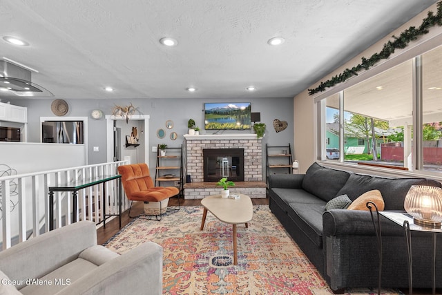 living area featuring wood finished floors, recessed lighting, a textured ceiling, and a fireplace