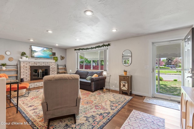 living area featuring wood finished floors, baseboards, a fireplace, and recessed lighting