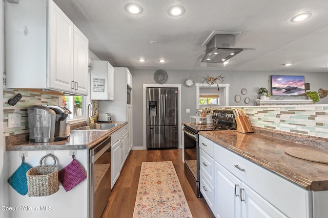 kitchen featuring appliances with stainless steel finishes, a sink, wall chimney exhaust hood, backsplash, and recessed lighting