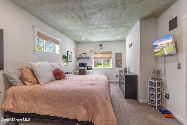 carpeted bedroom featuring multiple windows, a textured ceiling, and baseboards