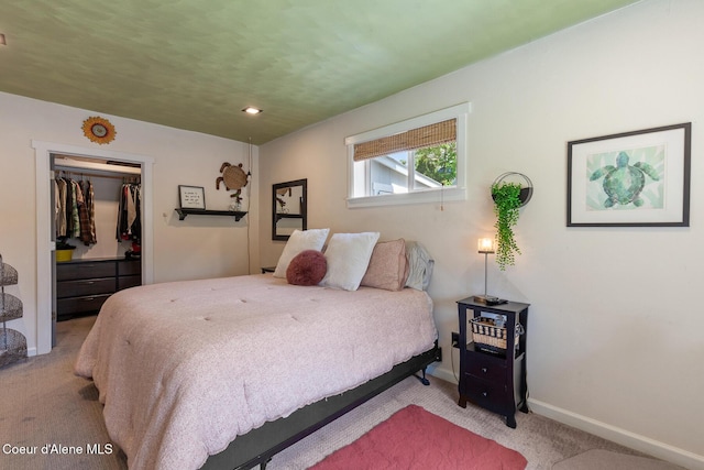 carpeted bedroom featuring baseboards, a walk in closet, and a closet