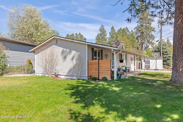 rear view of property featuring a shed, a lawn, an outdoor structure, and a patio