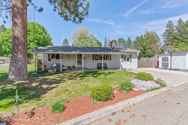 single story home with a shed, a chimney, an outbuilding, concrete driveway, and a porch